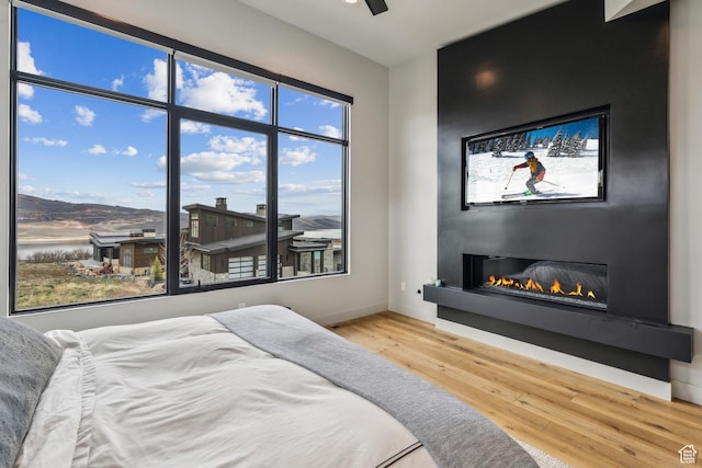11431 N Ursa Cir Unit 56, Heber City, UT 84032 - bedroom with a water view, baseboards, a ceiling fan, wood finished floors, and a fireplace