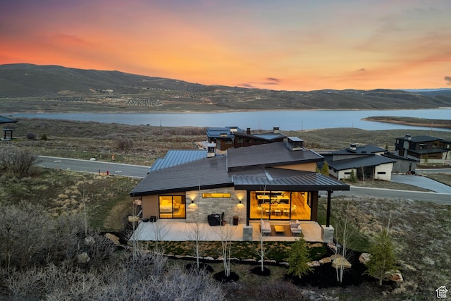 11431 N Ursa Cir Unit 56, Heber City, UT 84032 - back of house at dusk featuring stone siding, a standing seam roof, metal roof, and a water and mountain view