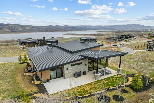 11431 N Ursa Cir Unit 56, Heber City, UT 84032 - rear view of property featuring a standing seam roof, stone siding, a patio, and metal roof