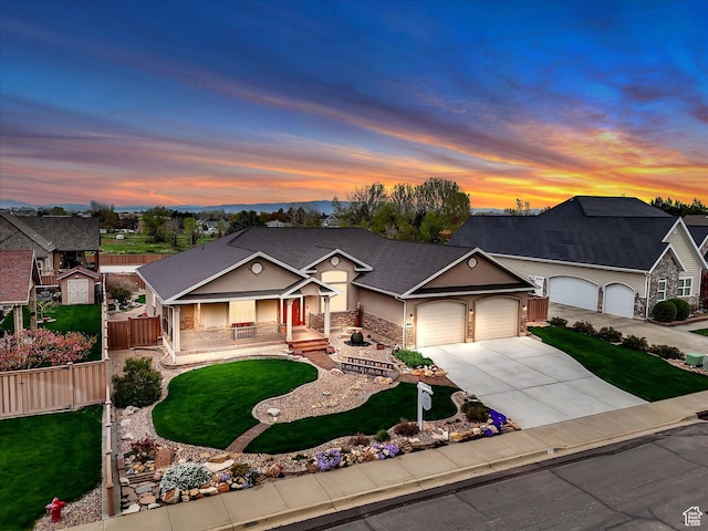 ranch-style home with an attached garage, driveway, a yard, and covered porch