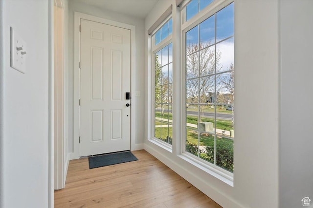 doorway to outside with light wood-style flooring and baseboards