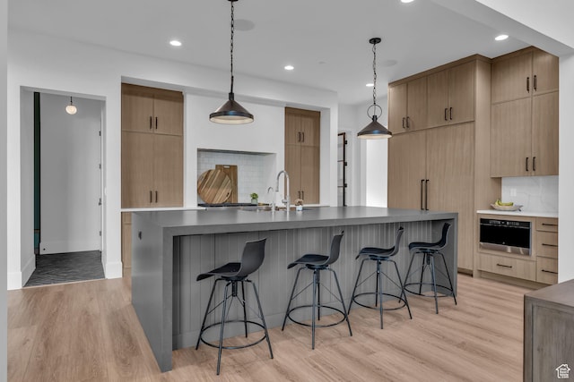 565 W Autumn Blaze, Woodland Hills, UT 84653 - kitchen with a breakfast bar area, tasteful backsplash, light wood-style floors, and a sink