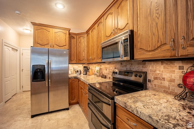 11855 S Cottage Side Way E, Draper, UT 84020 - kitchen featuring brown cabinetry, appliances with stainless steel finishes, tasteful backsplash, and light stone countertops