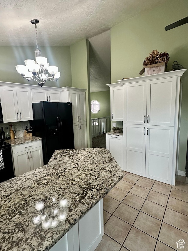 kitchen featuring a textured ceiling, black appliances, light tile patterned floors, an inviting chandelier, and white cabinets