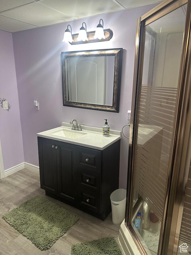 full bathroom featuring baseboards, wood finished floors, vanity, and a stall shower