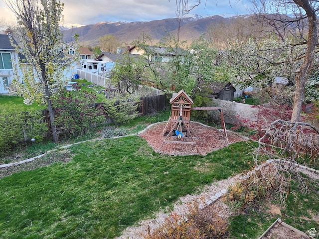 view of yard with a playground, a fenced backyard, and a mountain view