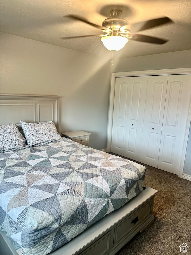bedroom featuring a textured ceiling, dark colored carpet, a closet, and ceiling fan