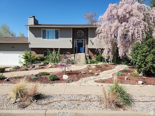 split foyer home with brick siding, entry steps, an attached garage, and a chimney