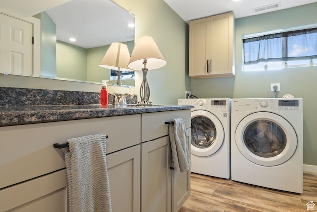 clothes washing area with washing machine and clothes dryer, cabinet space, visible vents, and a healthy amount of sunlight