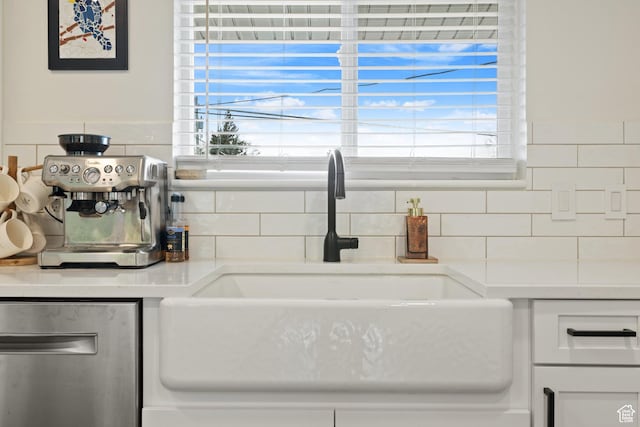interior details with white cabinets, light countertops, a sink, and tasteful backsplash