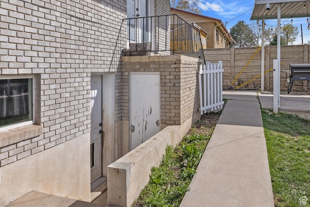view of side of home with fence and brick siding