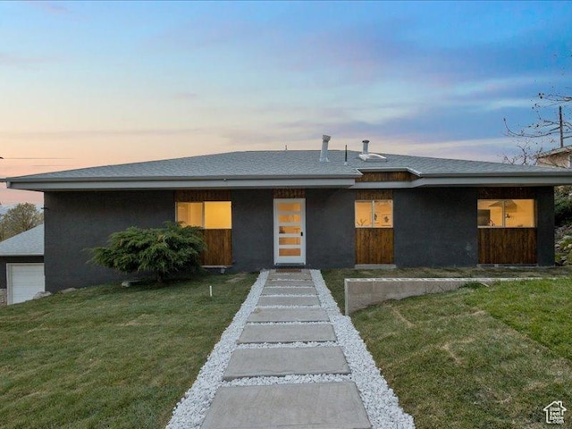 view of front of house featuring a front lawn, roof with shingles, and stucco siding