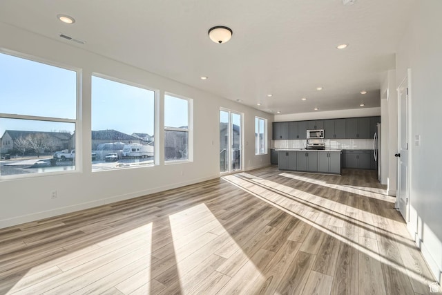 251 E Montgomery Ln, North Ogden, UT 84414 - unfurnished living room featuring baseboards, recessed lighting, visible vents, and light wood-type flooring