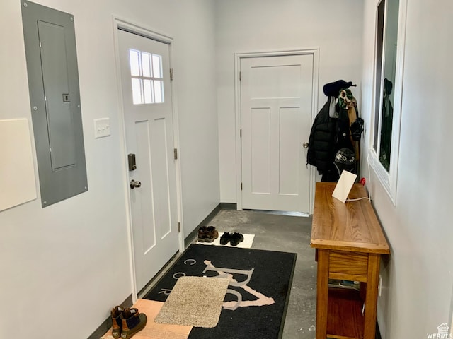 interior space with concrete flooring, electric panel, and baseboards