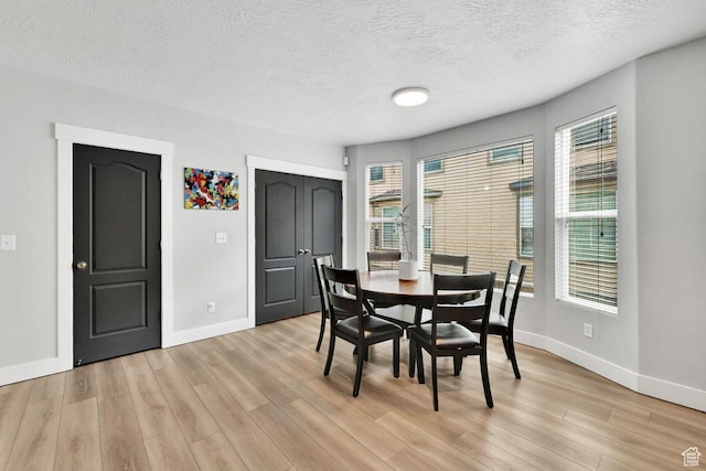 3708 S Luchars Ln W, Salt Lake City, UT 84115 - dining room featuring light wood-style flooring, baseboards, a wealth of natural light, and a textured ceiling