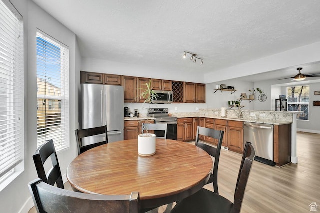 3708 S Luchars Ln W, Salt Lake City, UT 84115 - kitchen featuring light wood-style floors, a wealth of natural light, light countertops, a peninsula, and appliances with stainless steel finishes