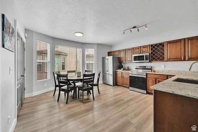 3708 S Luchars Ln W, Salt Lake City, UT 84115 - kitchen with a sink, light wood-style floors, baseboards, a textured ceiling, and appliances with stainless steel finishes