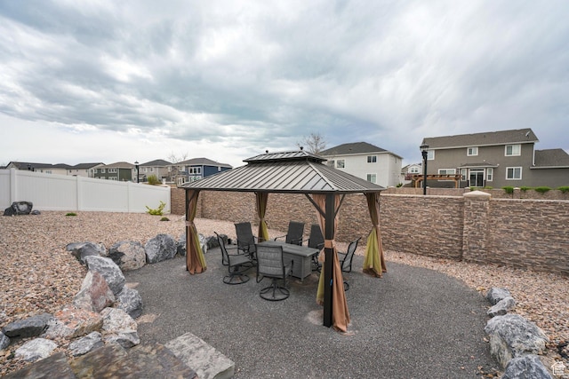 exterior space with a gazebo, a residential view, a fenced backyard, and outdoor dining space