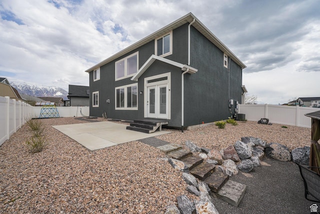 rear view of house featuring central AC, french doors, a fenced backyard, and a patio area