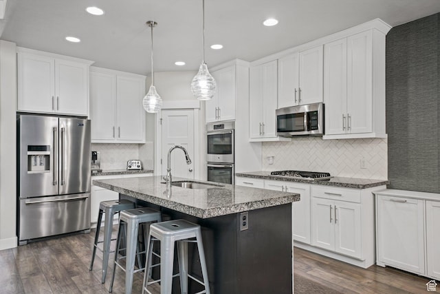 kitchen featuring white cabinetry, appliances with stainless steel finishes, decorative backsplash, and a sink