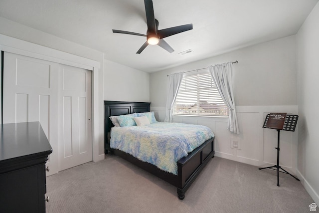 bedroom with light colored carpet, visible vents, wainscoting, and a closet