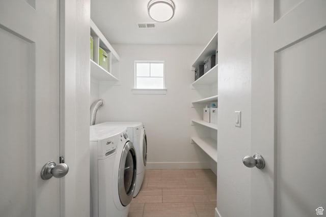 clothes washing area with laundry area, baseboards, washer and dryer, and visible vents