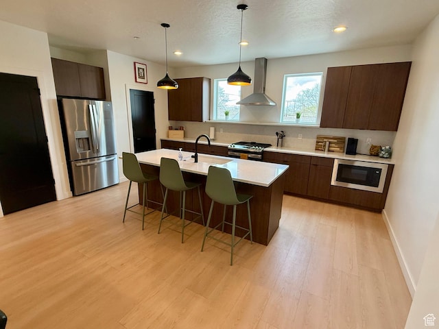 1739 S Main St E Unit 9, Salt Lake City, UT 84115 - kitchen featuring wall chimney range hood, a breakfast bar, modern cabinets, light countertops, and appliances with stainless steel finishes