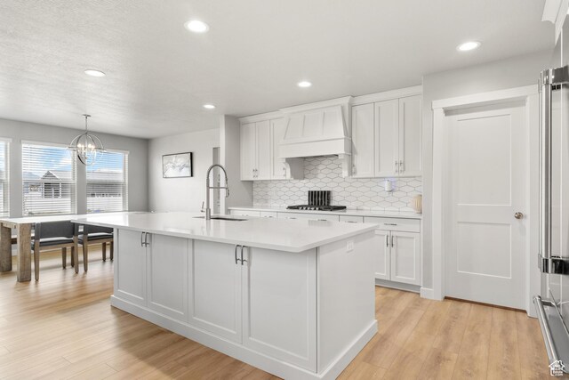 3698 S 5325 W, Hooper, UT 84315 - kitchen featuring a sink, stainless steel gas cooktop, an island with sink, light countertops, and custom range hood