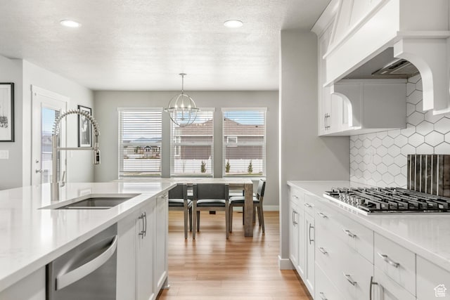 3698 S 5325 W, Hooper, UT 84315 - kitchen featuring light wood finished floors, backsplash, a sink, premium range hood, and appliances with stainless steel finishes