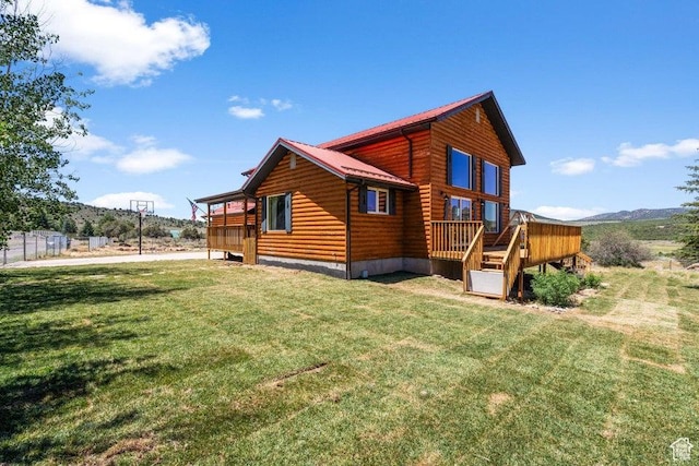 view of side of home featuring a lawn, metal roof, faux log siding, and a deck