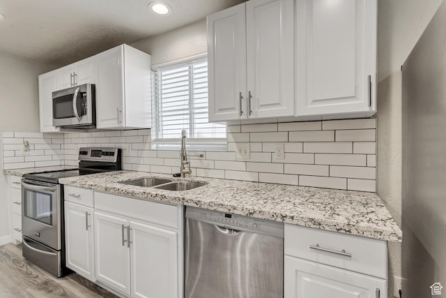 3306 N Fairfield Rd, Layton, UT 84041 - kitchen featuring white cabinets, appliances with stainless steel finishes, a sink, light wood-style flooring, and tasteful backsplash