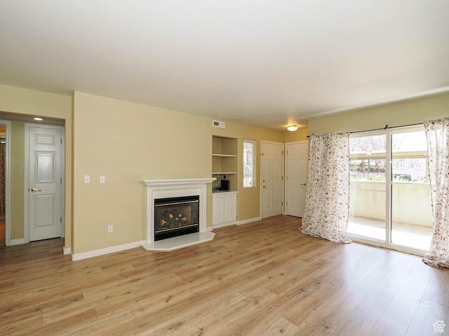 3832 S Big River Way W Unit 1, Salt Lake City, UT 84119 - unfurnished living room with baseboards, a glass covered fireplace, light wood-style floors, and visible vents