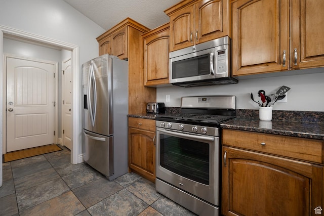 1808 E 2000 S, Naples, UT 84078 - kitchen with stainless steel appliances, dark stone countertops, stone finish floor, and brown cabinets