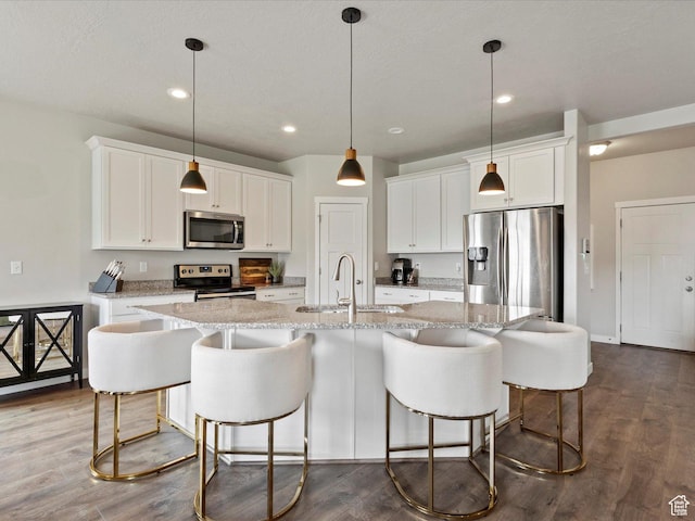 kitchen featuring white cabinetry, appliances with stainless steel finishes, a sink, and a center island with sink