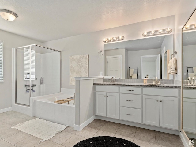 full bathroom with tile patterned flooring, double vanity, a bath, baseboards, and a stall shower