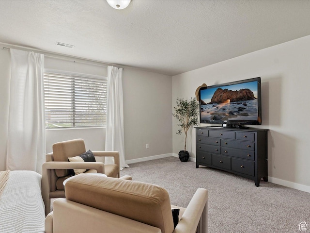 interior space featuring light colored carpet, baseboards, a textured ceiling, and visible vents