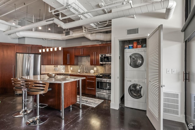328 W 200 S Unit 505, Salt Lake City, UT 84101 - kitchen featuring a sink, visible vents, stacked washer / dryer, backsplash, and appliances with stainless steel finishes