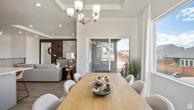 dining space featuring a tray ceiling, wood finished floors, recessed lighting, and an inviting chandelier