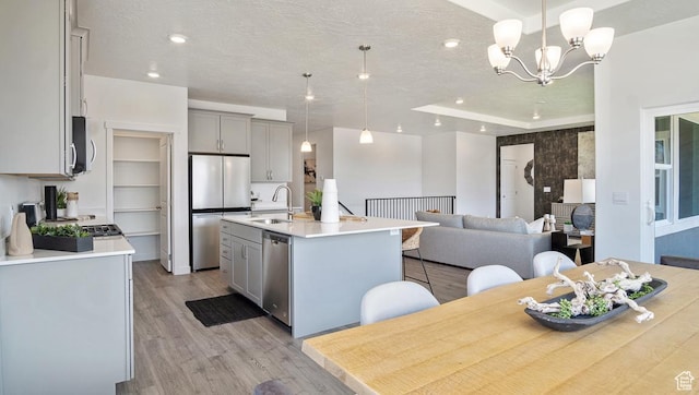 kitchen featuring a sink, a chandelier, light wood-type flooring, appliances with stainless steel finishes, and gray cabinetry