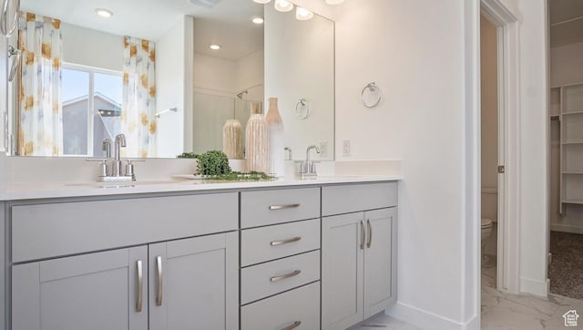 bathroom featuring baseboards, marble finish floor, a sink, and toilet