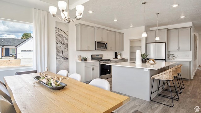 kitchen with stainless steel appliances, a center island, light wood-style floors, gray cabinets, and a breakfast bar