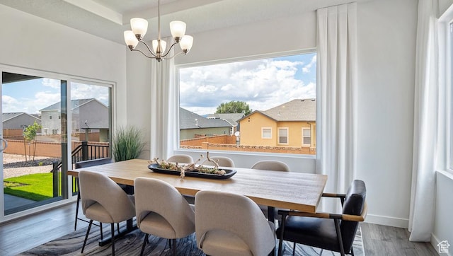 dining area featuring a chandelier, wood finished floors, and baseboards