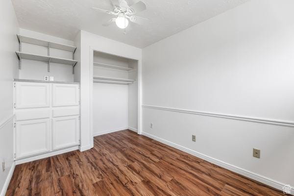 unfurnished bedroom with dark wood finished floors, a closet, a ceiling fan, and baseboards