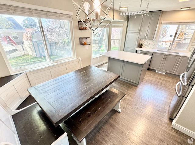 kitchen featuring a sink, light wood-style floors, a kitchen island, a wealth of natural light, and gray cabinetry
