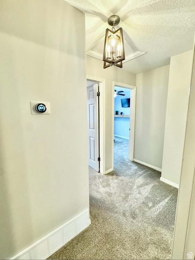 corridor featuring baseboards, carpet flooring, and a textured ceiling