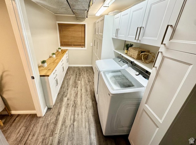 laundry area with light wood-style flooring, baseboards, independent washer and dryer, and cabinet space