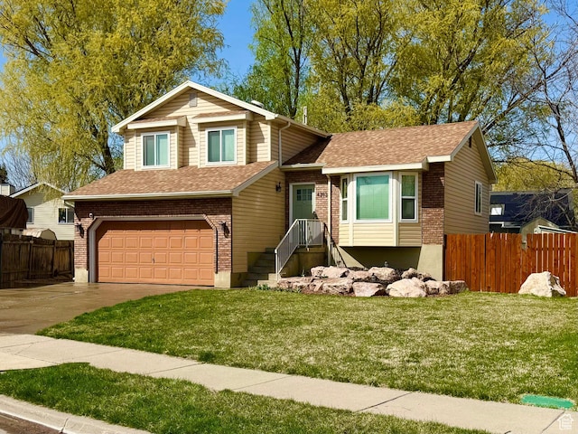 tri-level home with a front lawn, fence, and a garage