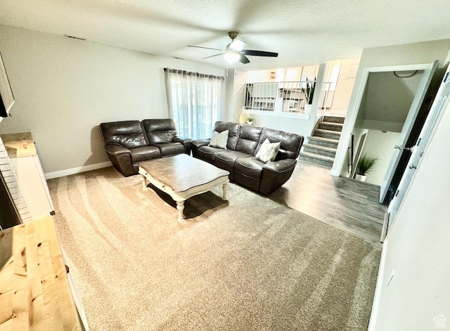 living area featuring carpet floors, a textured ceiling, a ceiling fan, and baseboards