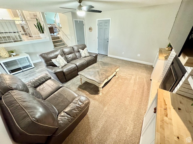 living area featuring a fireplace, baseboards, and ceiling fan