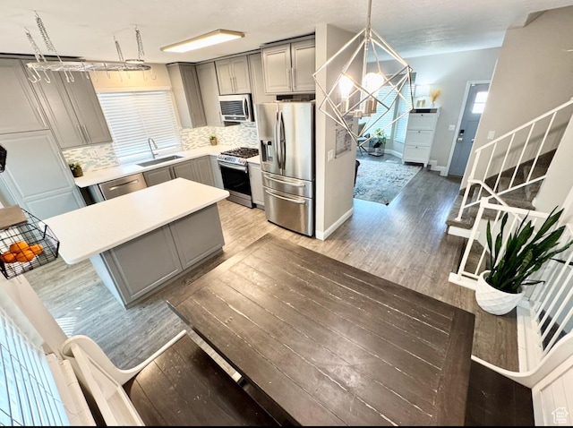kitchen featuring gray cabinetry, a sink, light wood-style floors, and appliances with stainless steel finishes